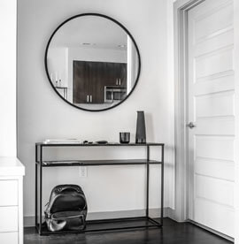 Didelis juodas apvalus veidrodis koridoriuje