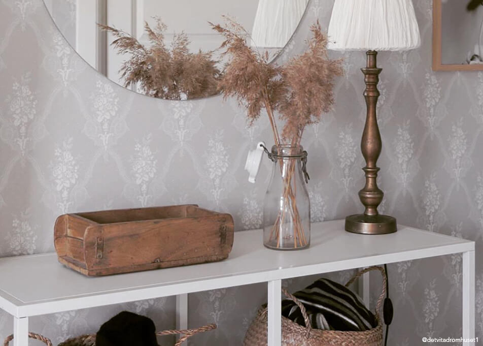Prieškambario interjeras – smulkių daiktų laikymas mediniame dubenyje, apvalus veidrodis, bronzinė lempa